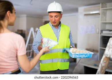 Woman Owner Of Apartment Giving Cash To Man Construction Painter. Payday Of Construction Worker.