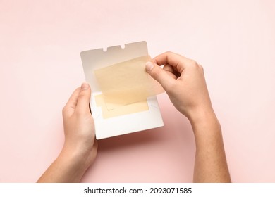Woman with package of oil blotting tissues on pink background, top view. Mattifying wipes