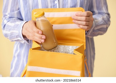 Woman Packing Bottle Of Juice Into Lunch Box Bag On Color Background, Closeup