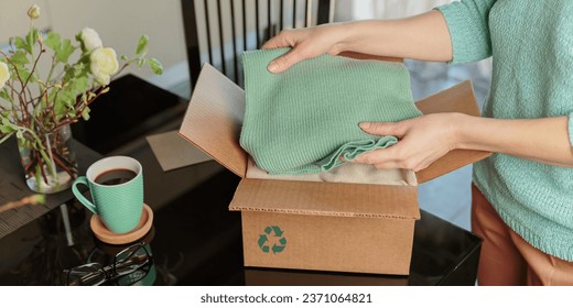 Woman packing box with used wardrobe for reuse. Reusing, recycling materials and reducing waste in fashion, second hand apparel idea. Circular fashion, zero waste concept
