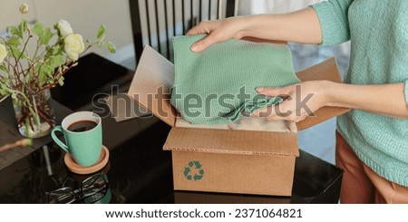 Woman packing box with used wardrobe for reuse. Reusing, recycling materials and reducing waste in fashion, second hand apparel idea. Circular fashion, zero waste concept