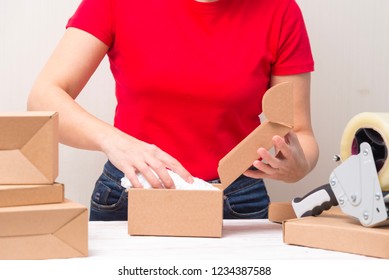 Woman packing cardboard boxes , picking and putting products