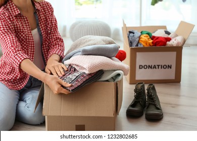 Woman Packing Clothes Into Donation Box At Home