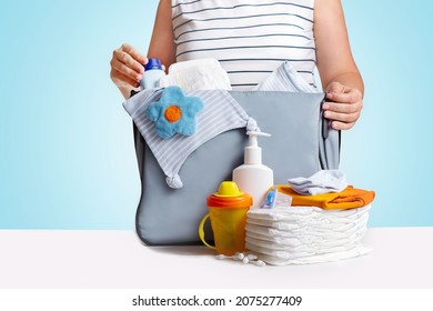 Woman Packing Diaper Bag On Blue Background.