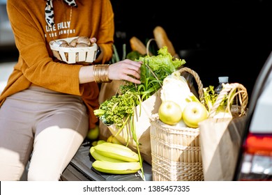 Woman Packing Fresh Food Into The Shopping Bags In The Car Trunk