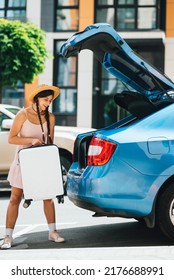 Woman Packing Her Suitcase Into Luggage Boot Of The Car.