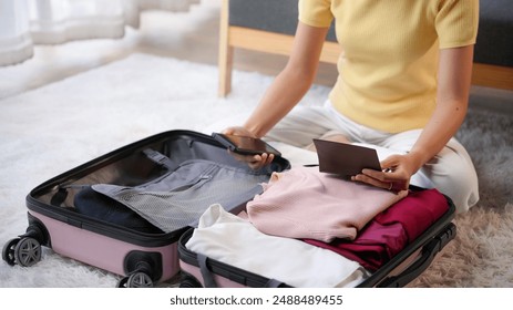 Woman packing her suitcase with passport, clothes, and travel essentials, preparing for an exciting trip - Powered by Shutterstock