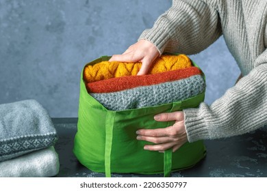 A Woman Packing Knitted Warm Sweaters In A Clothing Bag. Used Clothes. Slow Fashion And Donation Clothes Concept