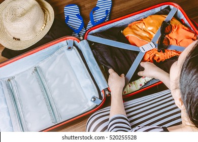 Woman packing a luggage on wooden floor