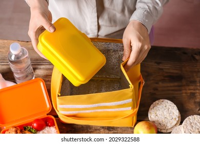 Woman Packing Meal Into Lunch Box Bag On Wooden Table