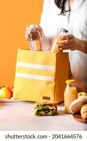 Woman Packing Meal Into Lunch Box Bag On Color Background