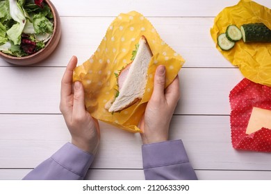 Woman Packing Sandwich Into Beeswax Food Wrap At White Wooden Table, Top View