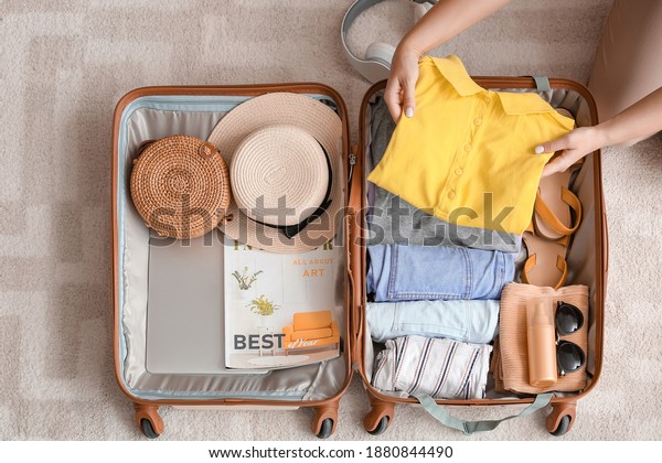 Woman packing\
suitcase at home. Travel\
concept
