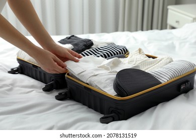 Woman packing suitcase for trip in bedroom, closeup - Powered by Shutterstock