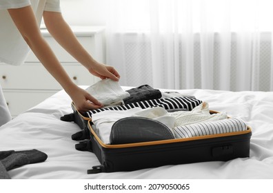 Woman Packing Suitcase For Trip In Bedroom, Closeup