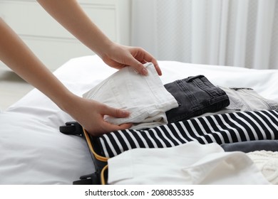 Woman Packing Suitcase For Trip In Bedroom, Closeup