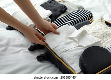 Woman Packing Suitcase For Trip In Bedroom, Closeup