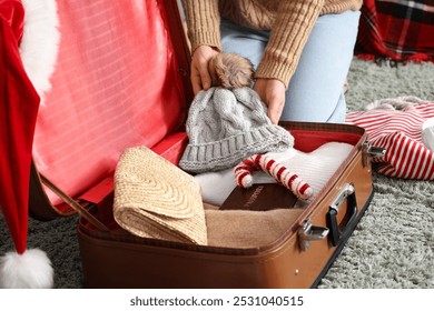 Woman packing warm clothes, passport and Christmas decor into suitcase at home, closeup - Powered by Shutterstock