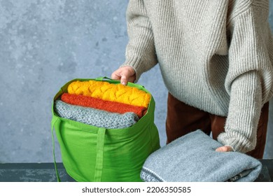 A Woman Packs Knitted Warm Sweaters In A Clothing Bag. Used Clothes. Slow Fashion And Donation Clothes Concept. High Quality Photo