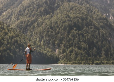 Woman Paddle boarding on a calm lake - Powered by Shutterstock