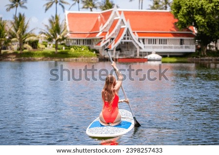 Woman paddle boarding on tranquil lake with tropical scenery. Adventure and exploration.