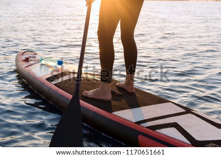 woman with a paddle on the blackboard. legs of a slender girl on stand up paddle board.