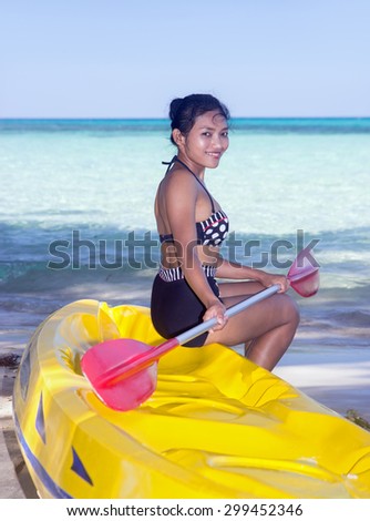 woman with a paddle sits on an inflatable boat on the sea beach