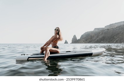 Woman Paddleboard Ocean - Relaxing on a paddleboard in the ocean near a rocky coastline. - Powered by Shutterstock