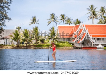 Woman paddleboarding on calm tropical waters near shore. Water sports and vacation.