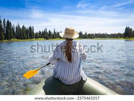 Woman paddling on an inflatable raft while floating the Snake River in Island Park, Idaho on an adventure vacation in the great outdoors. Near Yellowstone National Park