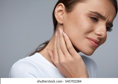 Woman In Pain. Closeup Of Beautiful Young Female Feeling Painful Toothache, Touching Face With Hand. Sad Stressed Girl Feeling Strong Teeth, Jaw Or Neck Pain. Dental Health And Care. High Resolution