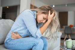 Woman In Painful Expression Holding Hands Against Belly Suffering Menstrual Period Pain, Lying Sad On Home Bed, Having Tummy Cramp In Female Health Concept