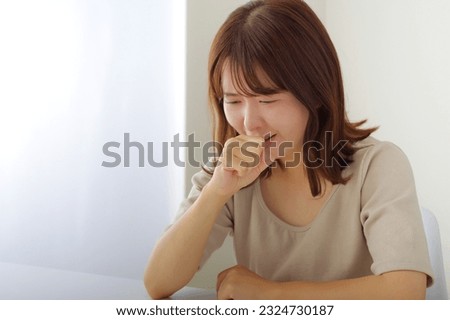 A woman with a painful expression who puts her hand on her mouth