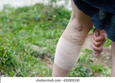 Woman with painful varicose and spider veins on her legs, applying compression bandage, self-helping herself. Vascular disease, varicose veins problems, painful unaesthetic medical condition concept.