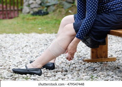 Woman with painful varicose and spider veins on her legs, applying compression bandage, self-helping herself. Vascular disease, varicose veins problems, painful unaesthetic medical condition concept.