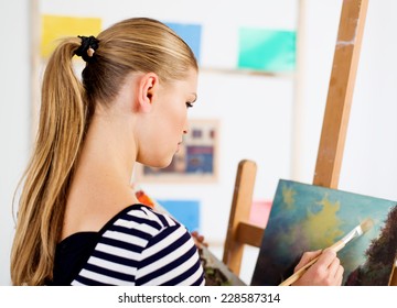 Woman painter creating new artwork in her artistic studio. Young female artist drawing oil picture of landscape.   - Shutterstock ID 228587314