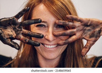 Woman Painter Hiding The Face With Her Painted Hands And Fingers In Black Paint. Focus On The Hand. Beautiful Woman With Perfect Skin.