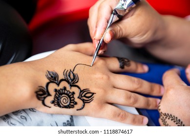 Woman Painting Black Henna Tattoo On A Girl's Hand.