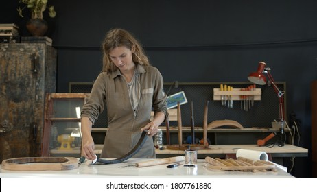 Woman Painting A Chair Leg In A Workshop, Restoration Process. Female Hands Painting A Wooden Detail With A Black Colour, Furniture Restoration