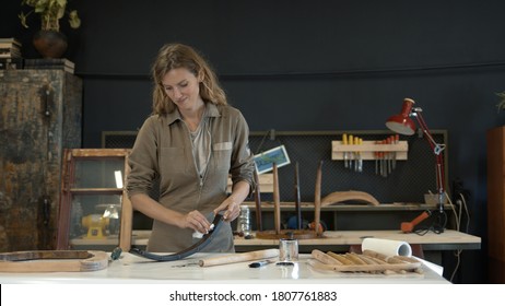 Woman Painting A Chair Leg In A Workshop, Restoration Process. Female Hands Painting A Wooden Detail With A Black Colour, Furniture Restoration