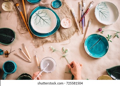 Woman painting clay pot with senior potter at workshop - Powered by Shutterstock