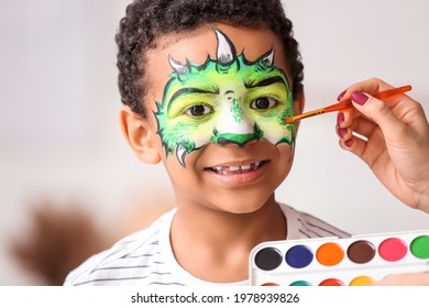 Woman painting face of African-American boy at home - Powered by Shutterstock