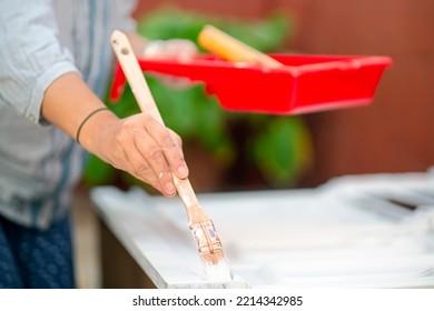 Woman Painting Furniture To Restore In Old Patio With Flowerpots And Whitewashed Walls  , Focus In Foreground