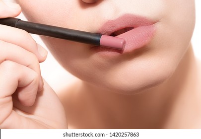 Woman painting her lips with pencil, close up