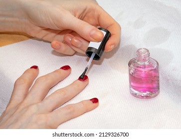 Woman Painting Nails With Red Nail Varnish And Top Coat