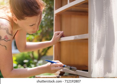 Woman Is Painting An Old Dresser Outdoor,  In White And Grey Shabby Chic Look