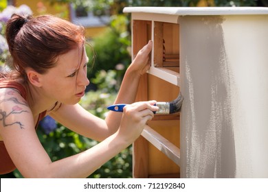 Woman Is Painting An Old Dresser Outdoor,  In White And Grey Shabby Chic Look