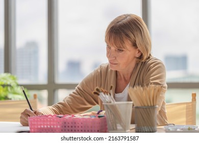 Woman Painting On A Canvas, Mature Middle Aged Woman Painting On Canvas At Home, Happy Retirement Concepts