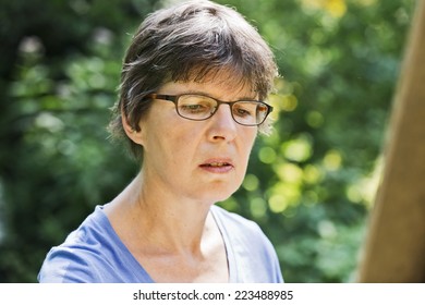 A Woman Painting A Picture In The Garden