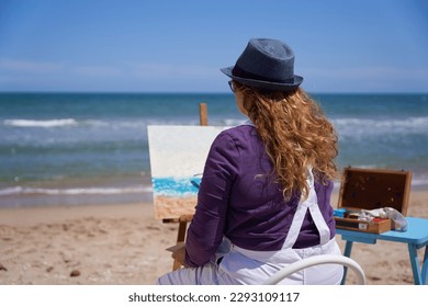 Woman painting a picture on the beach - Powered by Shutterstock